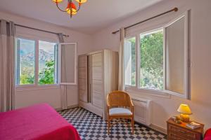 a bedroom with a bed and a chair and windows at Villa Kalliste in Porto Ota