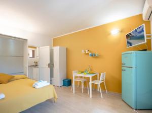 a room with a bed and a table and a refrigerator at Appartamenti LE TRE API in Porto Azzurro