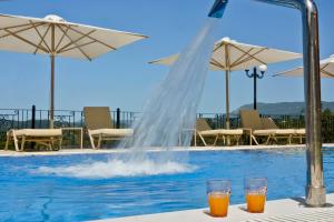 two glasses of orange juice sitting next to a swimming pool at Xristina in Dafnila