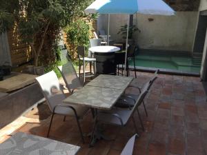 einen Tisch, Stühle und einen Regenschirm auf einer Terrasse in der Unterkunft Castel&Letti in Agde