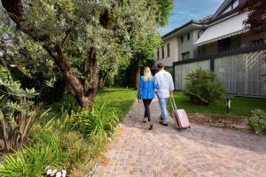 un hombre y una mujer caminando por una pasarela de ladrillo con equipaje en Like Home Boutique Hotel, en Azzano San Paolo