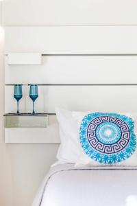 1 cama con almohada azul y blanca y 2 vasos en E & G figareto apartments 5 en Kanoni