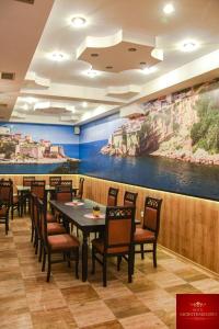 a dining room with tables and chairs and a painting at Hotel Montenegro in Struga