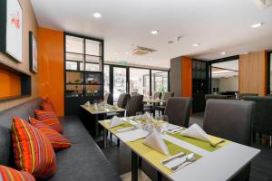 ein Restaurant mit Tischen, Stühlen und Fenstern in der Unterkunft KK Karon Kata Boutique Hotel in Kata Beach