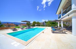 una piscina con sillas y sombrillas junto a un edificio en Villa MAGNIFICA with pool en Pinezici