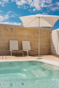 parasol i 2 krzesła przy basenie w obiekcie Sui Tetti Luxury Rooms w mieście Lecce