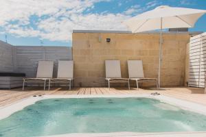 a swimming pool with two chairs and an umbrella at Sui Tetti Luxury Rooms in Lecce