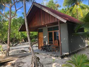 a small house on the beach with a table and chairs at Yenkoranu Homestay and Dive Center in Waisai