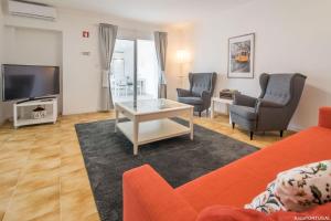 a living room with a couch and chairs and a tv at Santa Catarina Terrace in Estoril