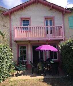 una casa con una mesa con una sombrilla rosa en Maison de 2 chambres avec piscine partagee terrasse amenagee et wifi a Lacanau a 2 km de la plage, en Lacanau