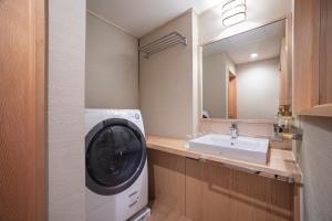 La salle de bains est pourvue d'un lave-linge et d'un lavabo. dans l'établissement kuon hotel kyoto shichijo, à Kyoto