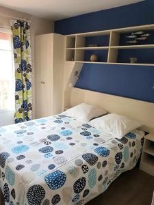 Schlafzimmer mit einem Bett mit einer blauen und weißen Bettdecke in der Unterkunft Maison de 3 chambres avec piscine partagee terrasse amenagee et wifi a Lacanau a 2 km de la plage in Lacanau