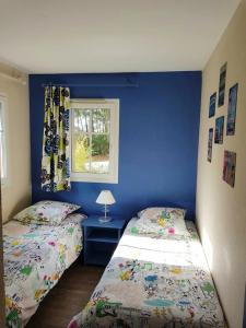 2 Betten in einem Schlafzimmer mit blauer Wand in der Unterkunft Maison de 3 chambres avec piscine partagee terrasse amenagee et wifi a Lacanau a 2 km de la plage in Lacanau