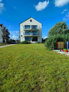 a white building with a grass field in front of it at Apartamenty Mistral in Jastarnia