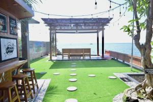 patio z zieloną trawą, ławką i oceanem w obiekcie Omah Kayu Villa w mieście Pasirputih
