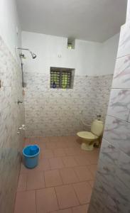 a bathroom with a toilet and a blue bucket at H Villa in Nilambūr