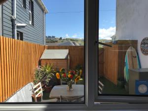una finestra con vista su un patio con tavolo e fiori di Flat Rocks, with parking, 100m from beach a Perranporth