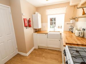 a kitchen with white cabinets and a window at 1 The Stables in Alston