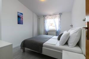 um quarto com uma cama com almofadas brancas e uma janela em Apartments SoMi em Porec
