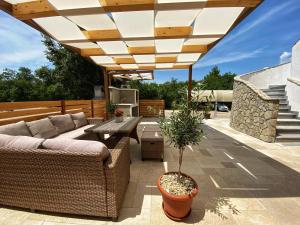 eine Terrasse mit einem Sofa und einem Tisch unter dem Dach in der Unterkunft Apartment Omanović in Čižići