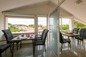 a dining room with a table and chairs and windows at Apartments SoMi in Poreč