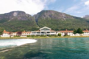 un resort sull'acqua con montagne sullo sfondo di Hotel Loenfjord Loen a Loen