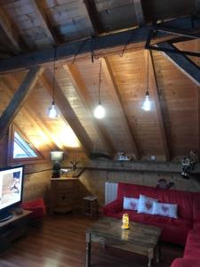 a living room with a red couch and a tv at Chalet 1830 au pied du MONT CHARVIN in La Savatte