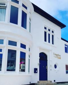 a white house with a blue door at Empress Hall Blackpool by Charles Alexander Short Stay - Sleeps 20 in Blackpool