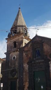an old building with a tower with a clock on it at CASETTA ROMANTICA Tra Etna e mare in Trecastagni