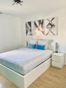 um quarto branco com uma cama com almofadas azuis em Apartment with Disneyland view! em Chessy