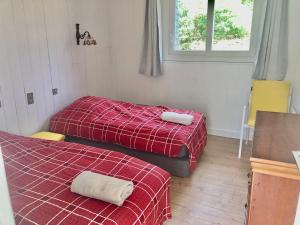 two beds in a room with a red blanket at Maison Nature Bretagne 3 chambres Plain-Pied in Langonnet
