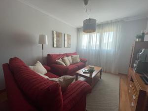 sala de estar con sofá rojo y mesa en Apartamento en Viveiro con aparcamiento gratuito, en Viveiro