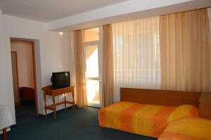 a hotel room with a bed and a television at Veda Guest House in Pomorie
