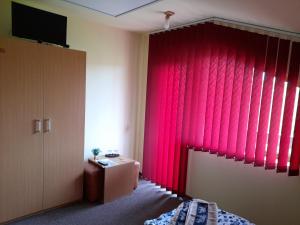 a bedroom with a red curtain and a tv at Casa cu flori in Bîrsău +28 photos