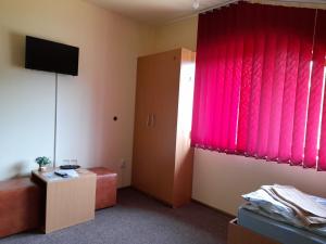 a room with a red curtain and a couch and a table at Casa cu flori in Bîrsău +33 photos