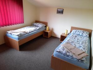 two twin beds in a room with red curtains at Casa cu flori in Bîrsău