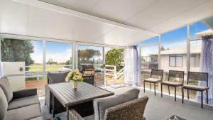 een woonkamer met een tafel en stoelen bij Fabulous Ocean and Reserve Views - Papamoa Beach in Papamoa