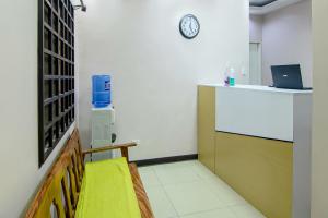 una habitación con un banco amarillo y un reloj en la pared en OYO 766 Ichehan Apartments, en Manila