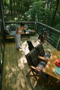 a woman standing on a deck with a dog at Baumhaus Silent 