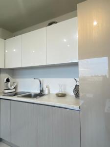 a kitchen with white cabinets and a sink at Brand new and modern apartment directly next to the metro station in Sofia +11 photos
