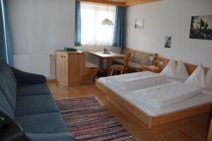 a bedroom with a bed and a couch and a table at Pension Oberhof in Sankt Lorenzen im Lesachtal