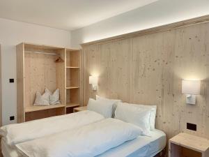 una camera da letto con letto, lenzuola e cuscini bianchi di Eurochalet a Campitello di Fassa