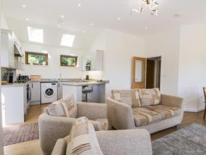 a living room with two couches and a kitchen at Little Barn in Grange Over Sands