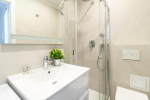 a white bathroom with a sink and a shower at Apartment Kröllgasse I contactless check-in in Vienna