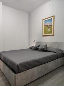 Cama en habitación blanca con una foto en la pared en Appartamento centrale, en SantʼAntìoco