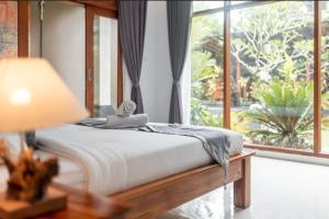 uma cama num quarto com uma grande janela em D'bunut villa ubud em Ubud