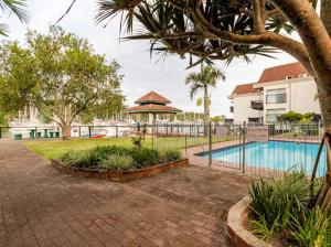 a swimming pool with a fence and trees at Mzingazi Waterfront Accommodation, On The Bay Waterfront Villa's in Richards Bay
