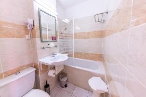 a bathroom with a toilet and a sink and a tub at Hotel Hélios in Cap d'Agde