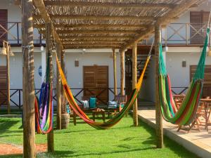 a group of hammocks hanging under a pergola at Pousada Ventos do Norte in Barra Grande
