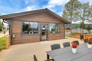 a house with a wooden deck with a table and chairs at Ballangen Camping in Narvik